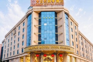 A hotel with a curved facade, large glass windows, and a sign reading 'Nature Hotel Four Seasons'. - Nature Hotel Four Seasons (Quanzhou)