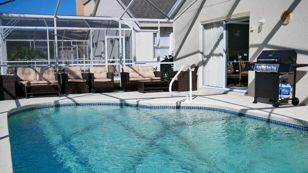 A swimming pool with lounge chairs and a barbecue grill. - Beautiful 5/5 Bedroom Home!!! (Davenport)
