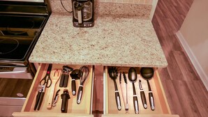 A kitchen with a granite countertop, a coffee maker, and two drawers with kitchen utensils. - Beautiful 5/5 Bedroom Home!!! (Davenport)