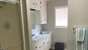 A bathroom with a shower, a sink, and a mirror. - Twin Oaks Cozy Getaway in Lake Charles (Lake Charles)