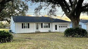 A single-story house with a dark roof, white siding, and a front porch. - Twin Oaks Cozy Getaway in Lake Charles (Lake Charles)