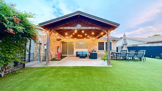 A covered patio area with string lights, a seating arrangement, and a lawn. - Near Highways, Family Friendly, Garage, Foosball, Grill, Dart, Tesla Charger (Plano)