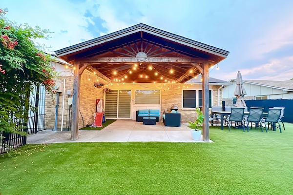 Nice backyard with a gazebo, an 8-person dining set, corn hole, and kid's toys.