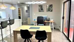 Un espace repas moderne avec une table en bois, des chaises noires et des luminaires suspendus.