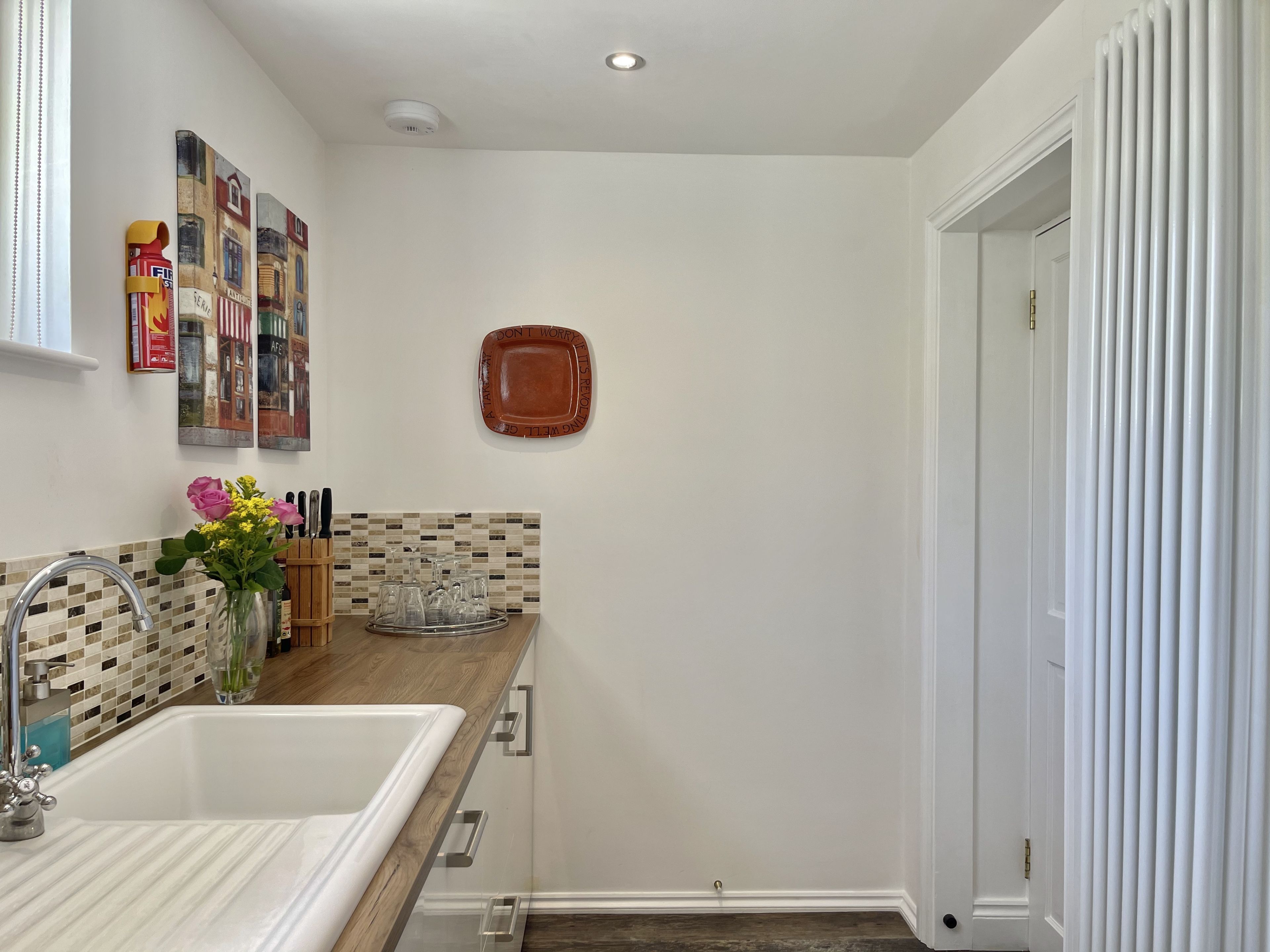 A modern kitchen with a white sink, wooden countertop, and a decorative tile backsplash.