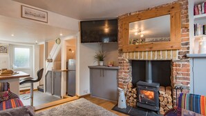 A cozy living room with a fireplace, a television mounted on the wall, and a bookshelf.