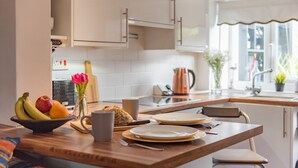 A modern kitchen with a wooden countertop, a bowl of fruit, a coffee maker, and a window with a view of the outdoors.