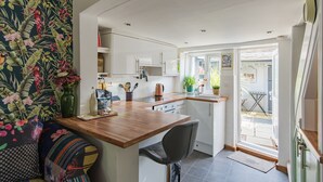 A compact kitchen with white cabinets, a wooden countertop, and a small dining area.