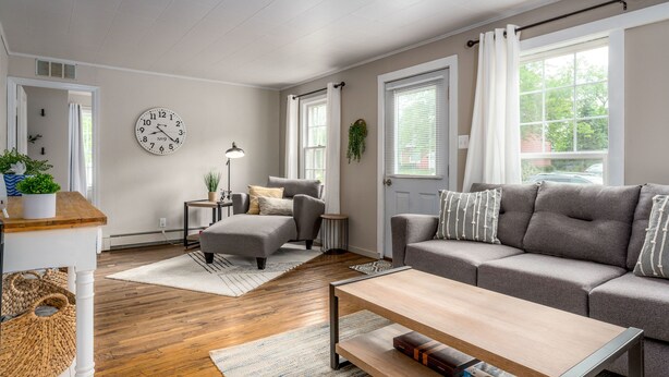 Ein Wohnzimmer mit einer Couch, einem Couchtisch und einer Uhr an der Wand.