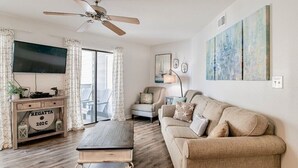 Un salon avec un canapé, une table basse, un téléviseur et un ventilateur de plafond.