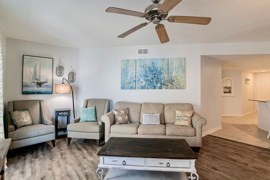 A living room with a ceiling fan, a sofa set, a coffee table, and artwork on the walls.