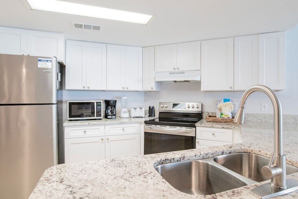 A modern kitchen with white cabinets, stainless steel appliances, and a granite countertop.