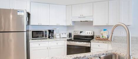 A modern kitchen with white cabinets, stainless steel appliances, and a granite countertop.