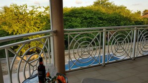 Ein Balkon mit einem Glastisch, einer Flasche und einem Glas.