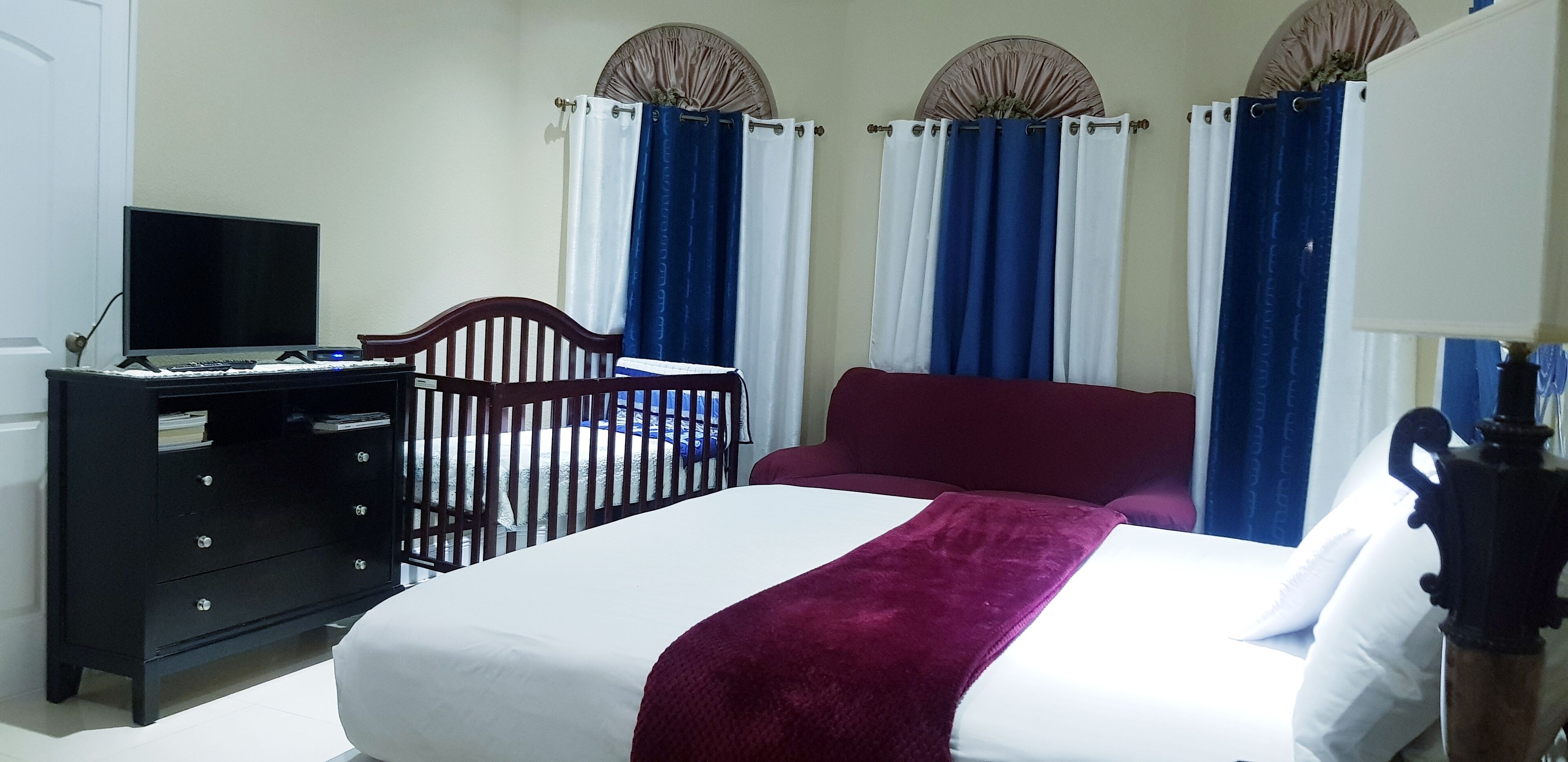 Une chambre d’hôtel avec un lit, un bureau avec un ordinateur, une commode et des rideaux.