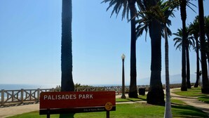 Un panneau indiquant l’entrée du parc de Palisades à Santa Monica, avec une vue sur l’océan et les palmiers.
