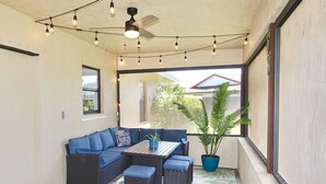 Eine überdachte Terrasse mit Sofa, Tisch und einer Topfpflanze.