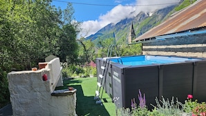Une piscine entourée d’un jardin où poussent différentes espèces de plantes, ainsi que d’une structure en pierre.