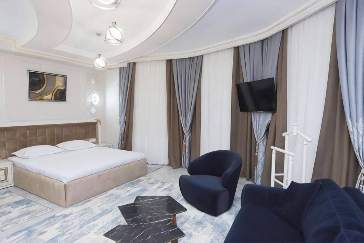 Quarto de hotel com uma cama grande, um sofá, uma TV e uma TV de tela plana na parede.