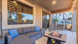 Un patio exterior con un sofá, una chimenea y vistas al jardín trasero.
