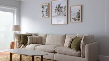 A living room with a beige sofa, a round coffee table, and three framed pictures on the wall.