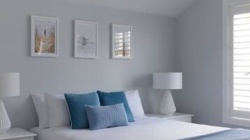 A bedroom with a bed, two bedside tables, and three wall-mounted pictures.