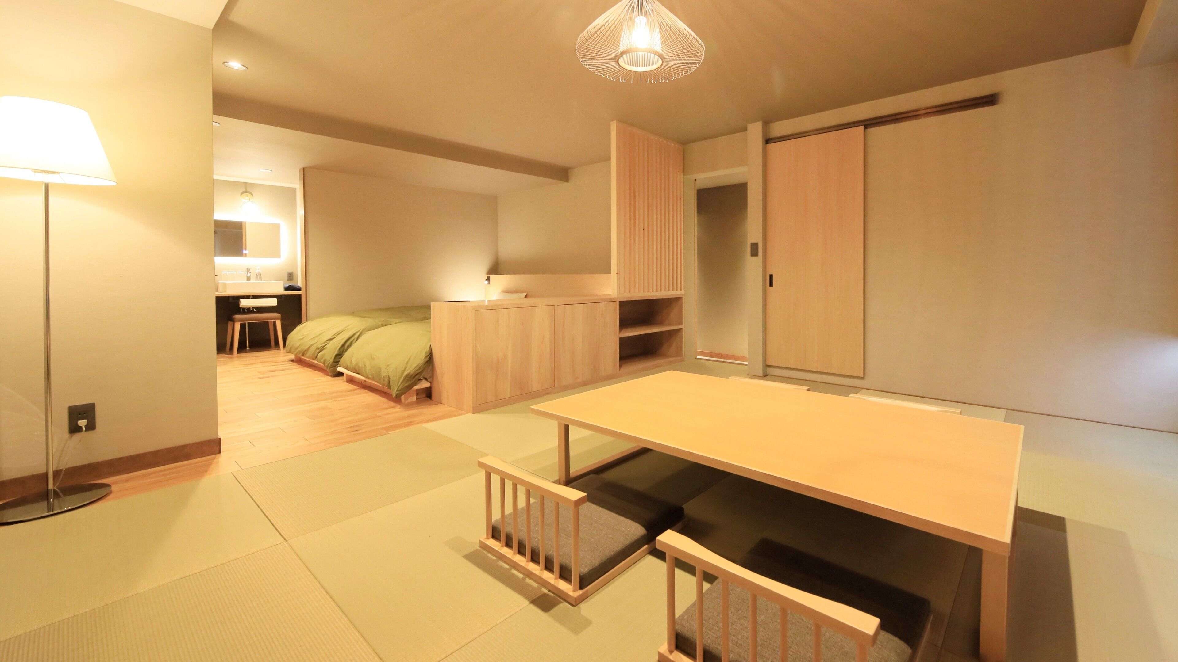 A modern, minimalist bedroom with a bed, bedside table, and a desk area.
