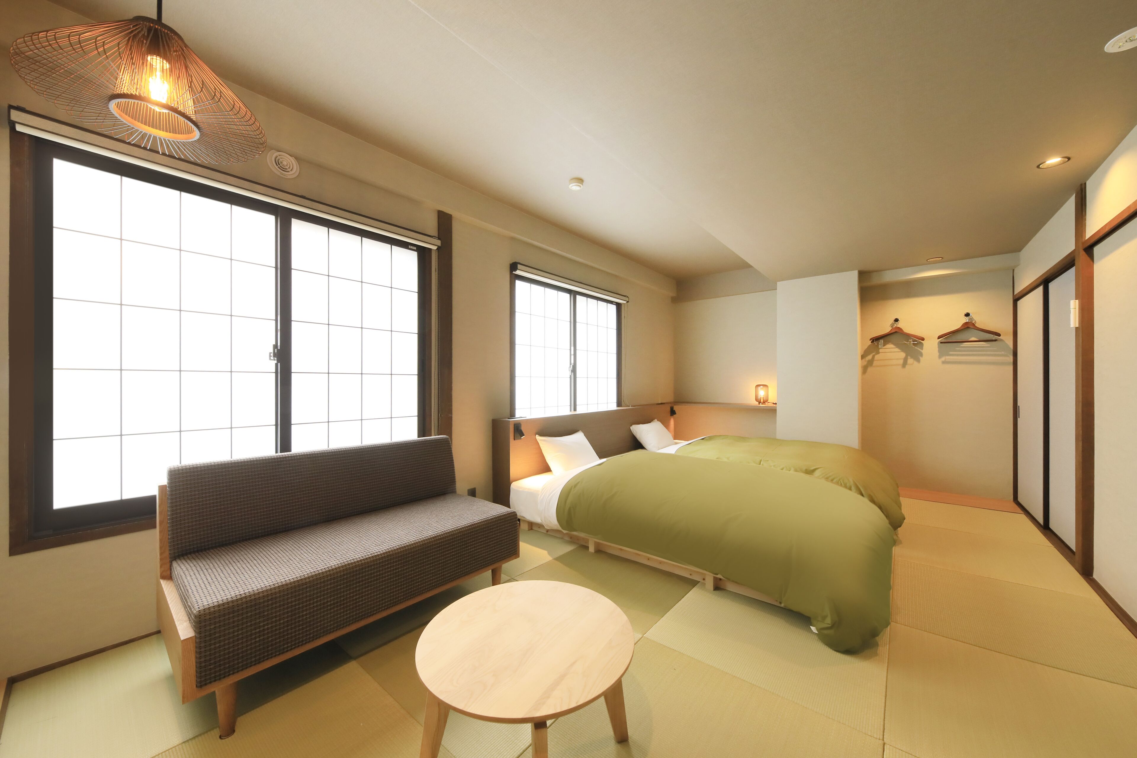 A traditional Japanese-style room with tatami flooring, a futon bed, a low wooden table, and a cushioned bench.