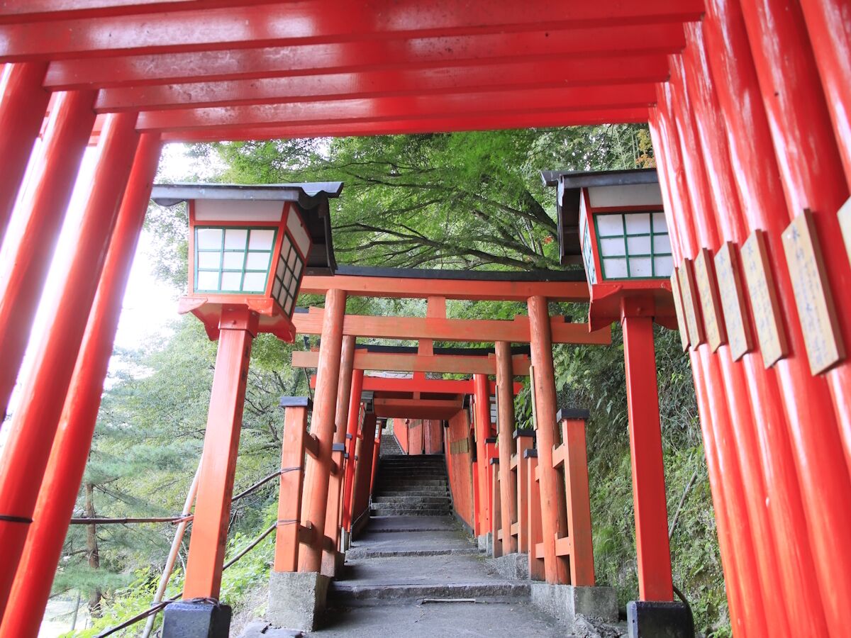 Um portal vermelho torii que leva a um edifício tradicional japonês com telhado de telhas.