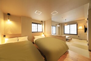 A modern hotel room with two beds, a small desk, and large windows.
