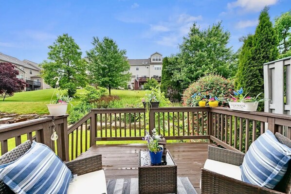A wooden deck with wicker furniture and potted plants.