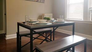 A dining area with a table set for four, a bench, and a painting on the wall. - Comfy Bed/Free Parking&Wifi /NearHosp/ORD/MDW/DT (Berwyn)