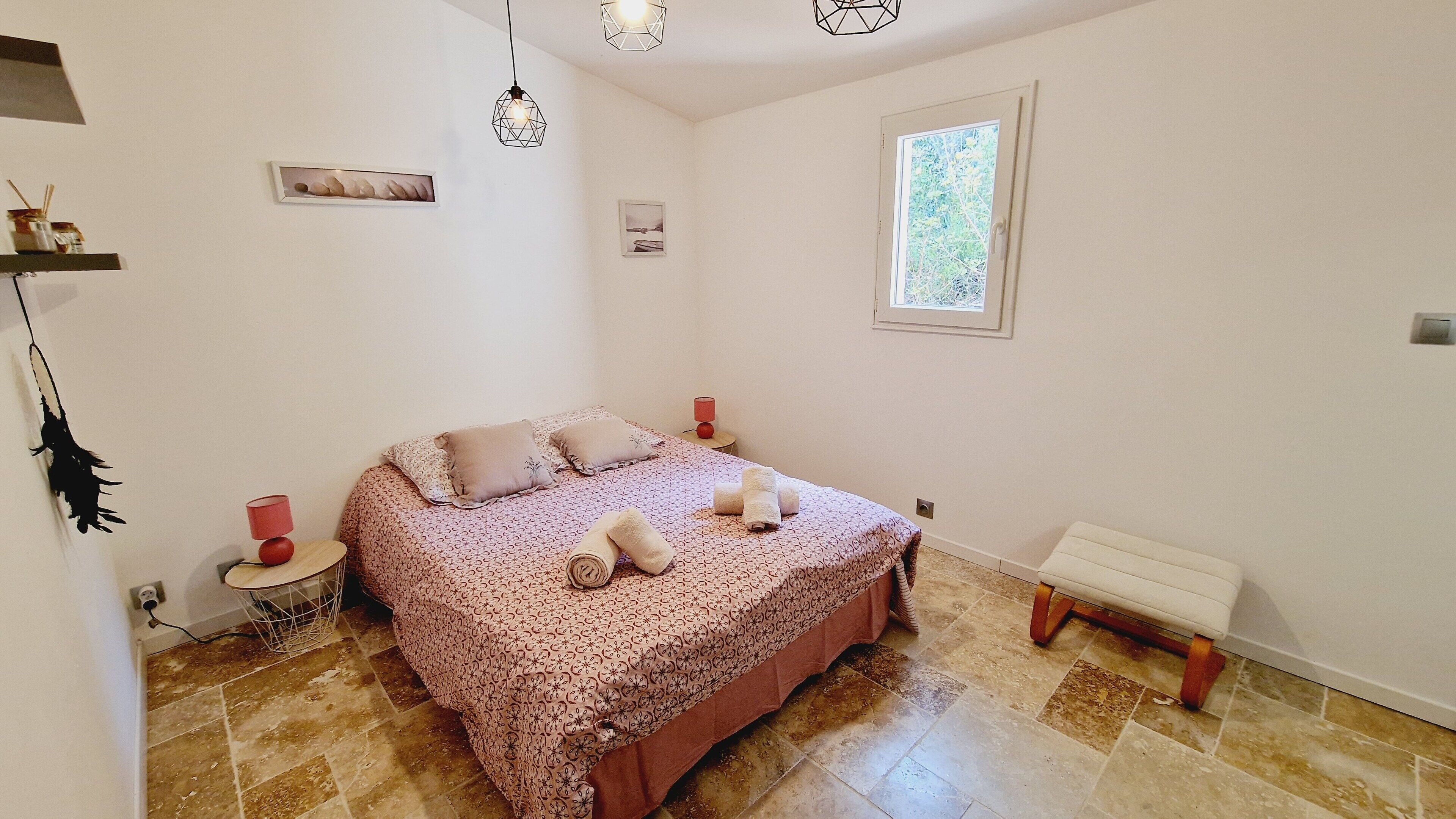 Ein Schlafzimmer mit einem Bett, Nachttischen, einem Fenster und einer Bank.
