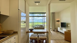 A modern living room with a large window, a TV, and a dining area.