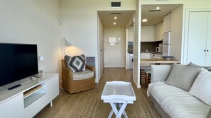 A living room with a TV, a sofa, a chair, and a small table.