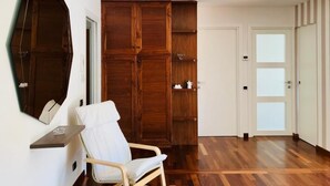 Ein Zimmer mit einem Holzschrank, einem weißen Stuhl und einer Tür mit satinierten Glasfeldern.
