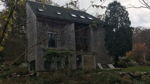 A rustic wooden house with a sloped roof, multiple windows, and a front porch. - Walk to the ocean, very private. Secluded, woodsy location.  (Gloucester)