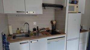 A modern kitchen with white cabinets, a stainless steel sink, and a black range hood. - 0000000000 (rognes)