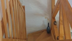 A staircase with wooden railings and a white textured wall.