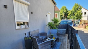 An outdoor patio with wicker furniture, potted plants, and a small table.