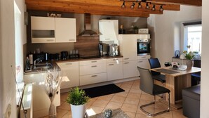A modern kitchen with wooden beams, white cabinets, and a dining area with a table and chairs.