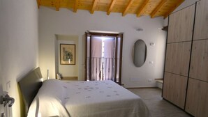 A bedroom with a bed, a bedside table, a wardrobe, a mirror, and a door leading to a balcony. - Escape To Umbria, Little Alley (Porchiano del Monte)