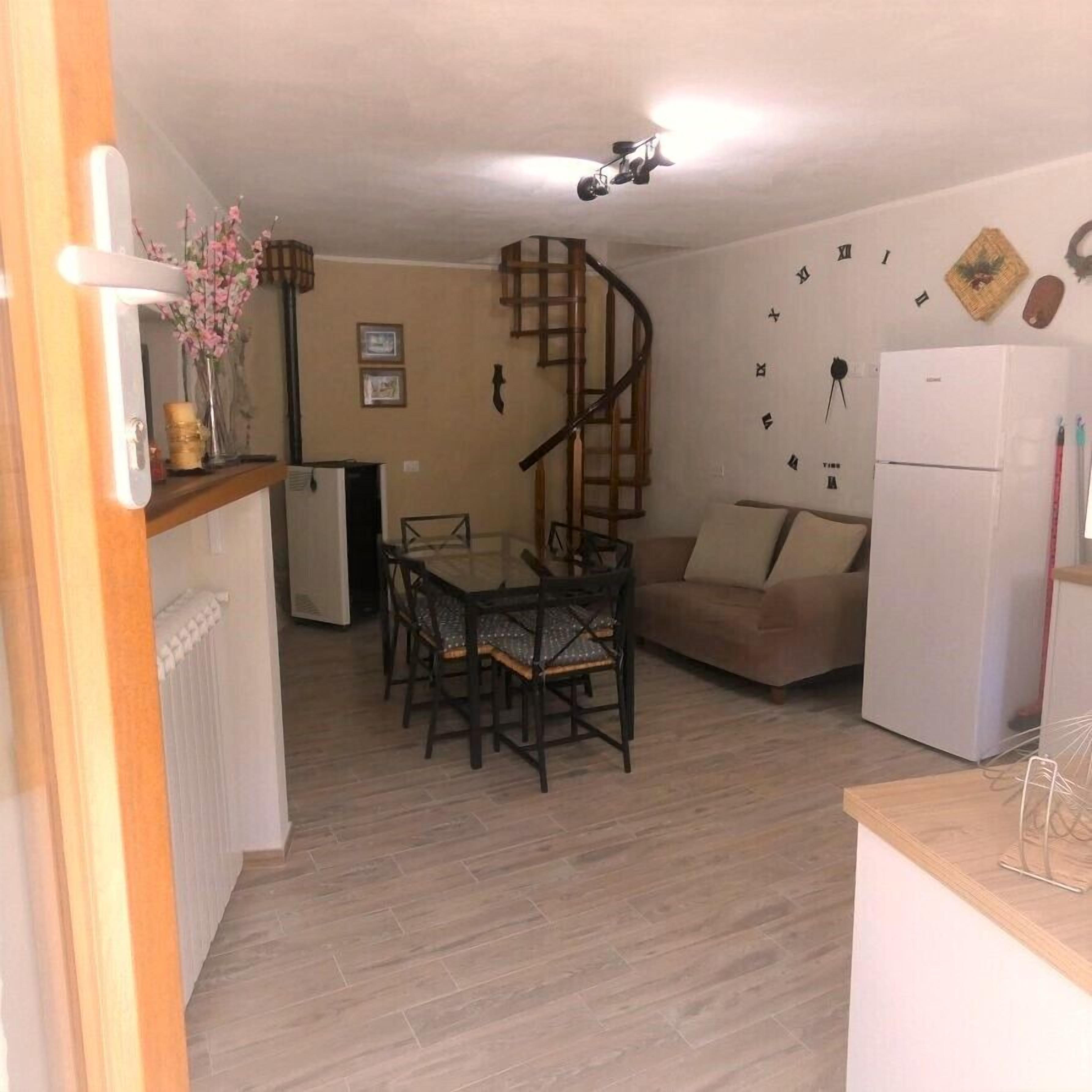 Una cucina compatta con zona pranzo, una scala a chiocciola e un frigorifero.