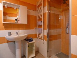 Bathroom features a pedestal sink, mirror, and glass-enclosed shower area.