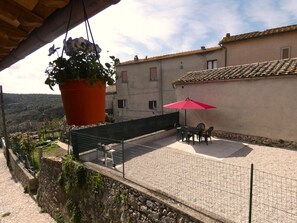 Relax on the terrace with a scenic view, featuring a dining table and chairs under a shaded area.