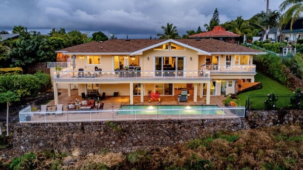 A two-story house with a swimming pool, a balcony, and a stone retaining wall. - Paradise Found (Waikoloa Village)