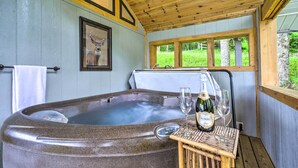 Un jacuzzi con panel de control, dos copas de vino y una botella de cerveza Korbel sobre una mesa de madera.