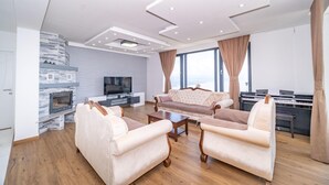 A modern living room with a fireplace, a sofa set, a television, and a piano. - Luxurious home in Matulji (Matulji)
