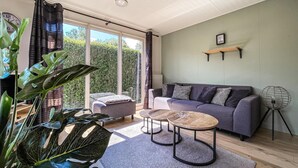 A modern living room with a grey sofa, two round coffee tables, and a large plant.
