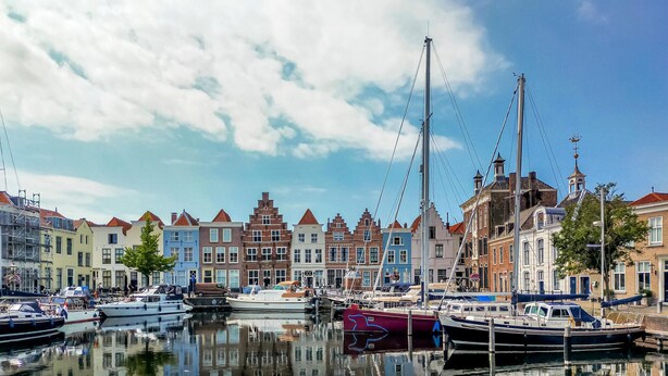 A marina with boats docked, surrounded by colorful buildings with traditional architecture.